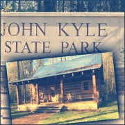 Rustic cabin in front of a sign for John Kyle State Park